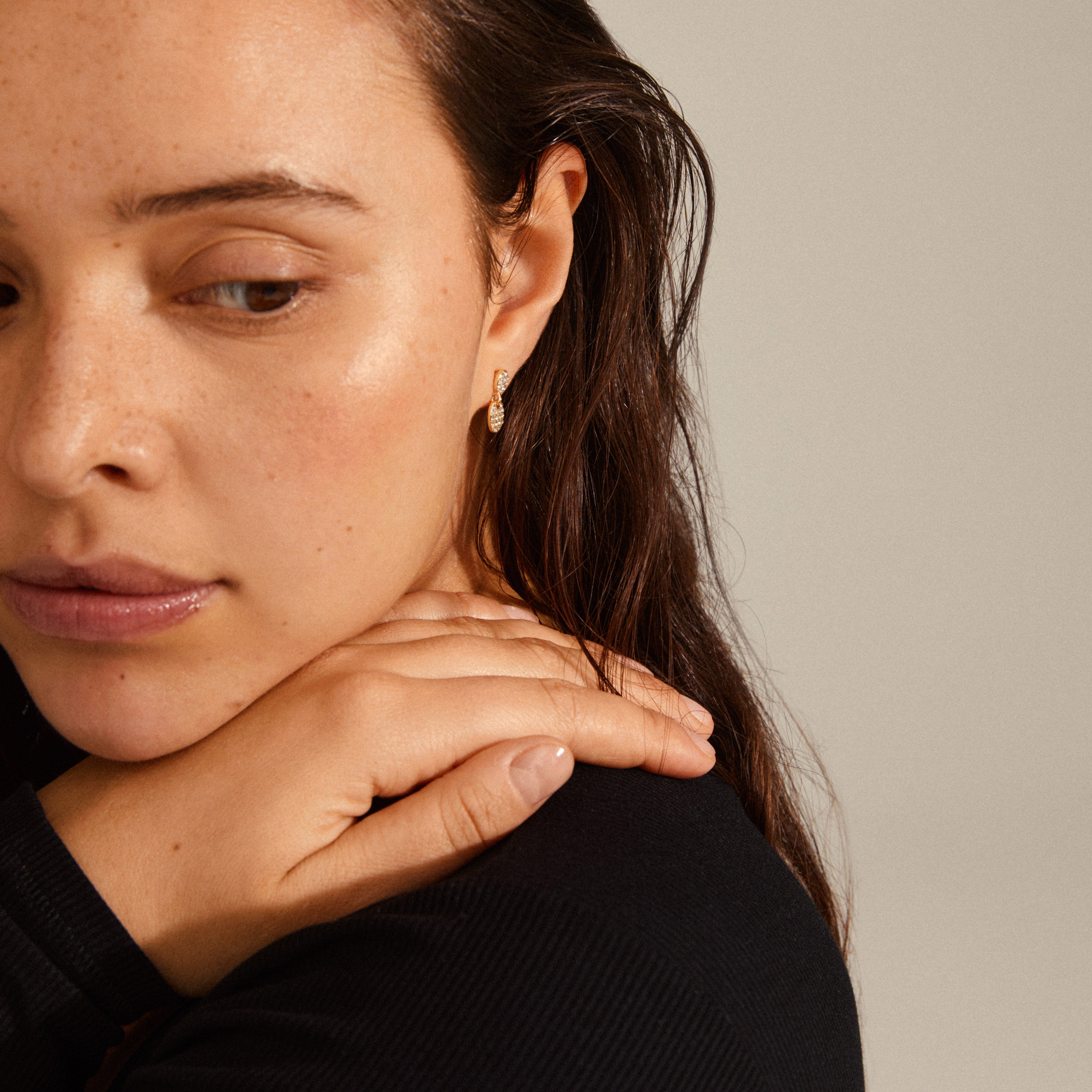 BEAT crystal earrings gold-plated, featuring oval pendants with Preciosa crystals, delicately worn by a woman touching her shoulder.
