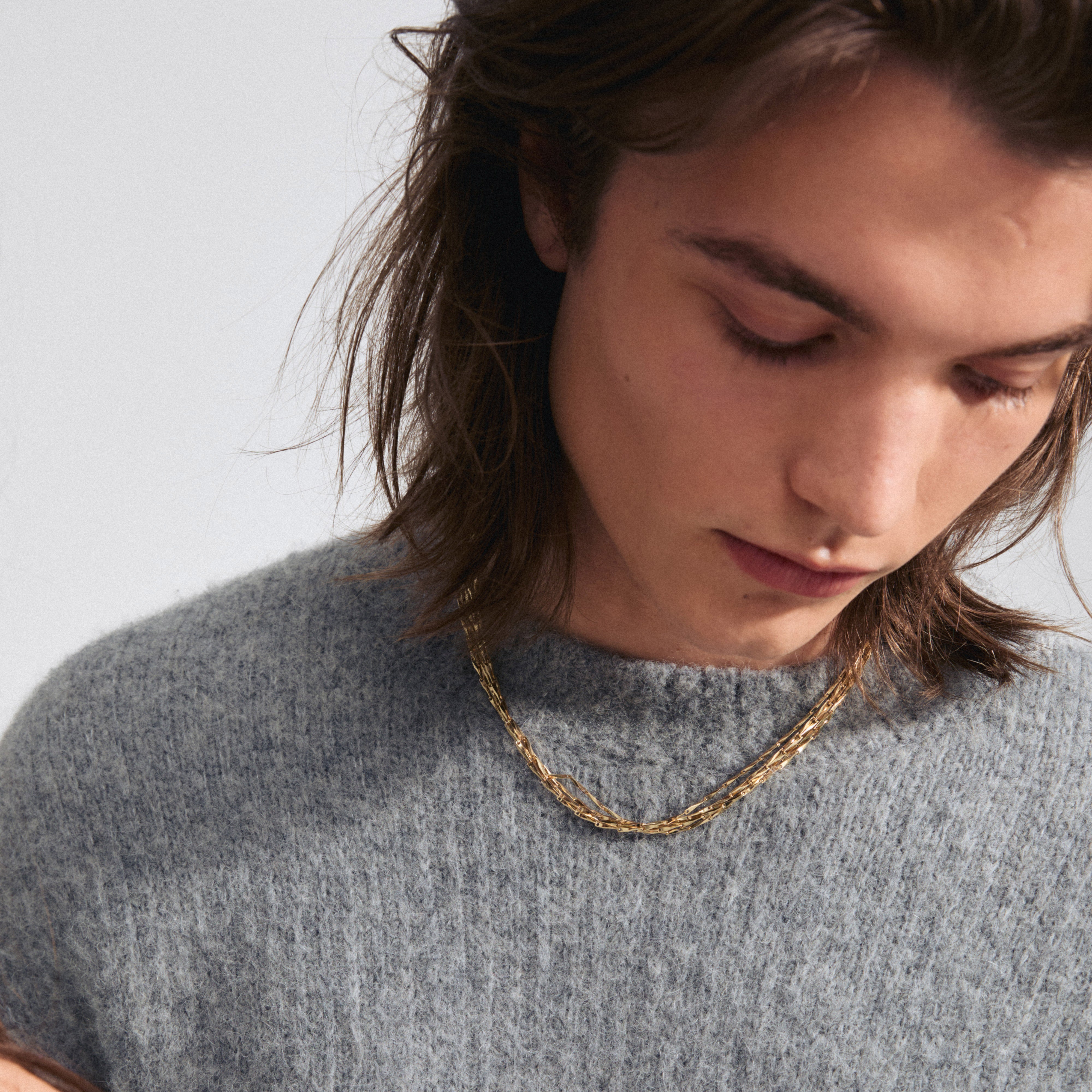 Man wearing the CONNECT necklace, a gold-plated, layered accessory with twisted melon seed links, adding shine and texture to his look.
