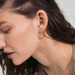 Gold-plated CONNECT crystal earrings with wavy design and Preciosa crystals, worn by a woman, showcasing their elegance and eco-friendly craftsmanship.