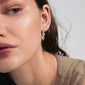 CONNECT crystal earrings gold-plated, featuring wavy gold-plated oval hoops with shiny Preciosa crystals, worn by a woman showcasing elegance and style.