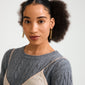 Close-up of Pilgrim's PHASE earrings gold-plated, featuring short gold chains, worn by a person with natural hair, embodying urban style and classic elegance.