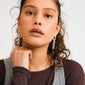 Young woman wearing PHASE earrings, silver-plated with airy, movable chain-links from Pilgrim. Her curly hair is pulled back, emphasizing the earrings' elegant design.