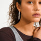 Young woman wearing PHASE earrings silver-plated by Pilgrim; long cable chain style, resting hand on collarbone, showcasing the earrings' elegant and urban design.