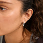 Close-up of a person wearing PHASE oval hoops silver-plated by Pilgrim, featuring linked silver hoops with sparkling stones and a convenient click clasp.