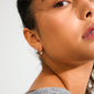 Close-up of a person wearing PHASE small silver-plated hoops from Pilgrim, highlighting their chunky silhouette and glossy finish against warm-toned skin.