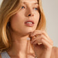 CHAKRA Quartz Crystal necklace gold-plated, worn by a woman holding the pendant, showcasing the clear quartz stone's raw beauty and elegant chain.