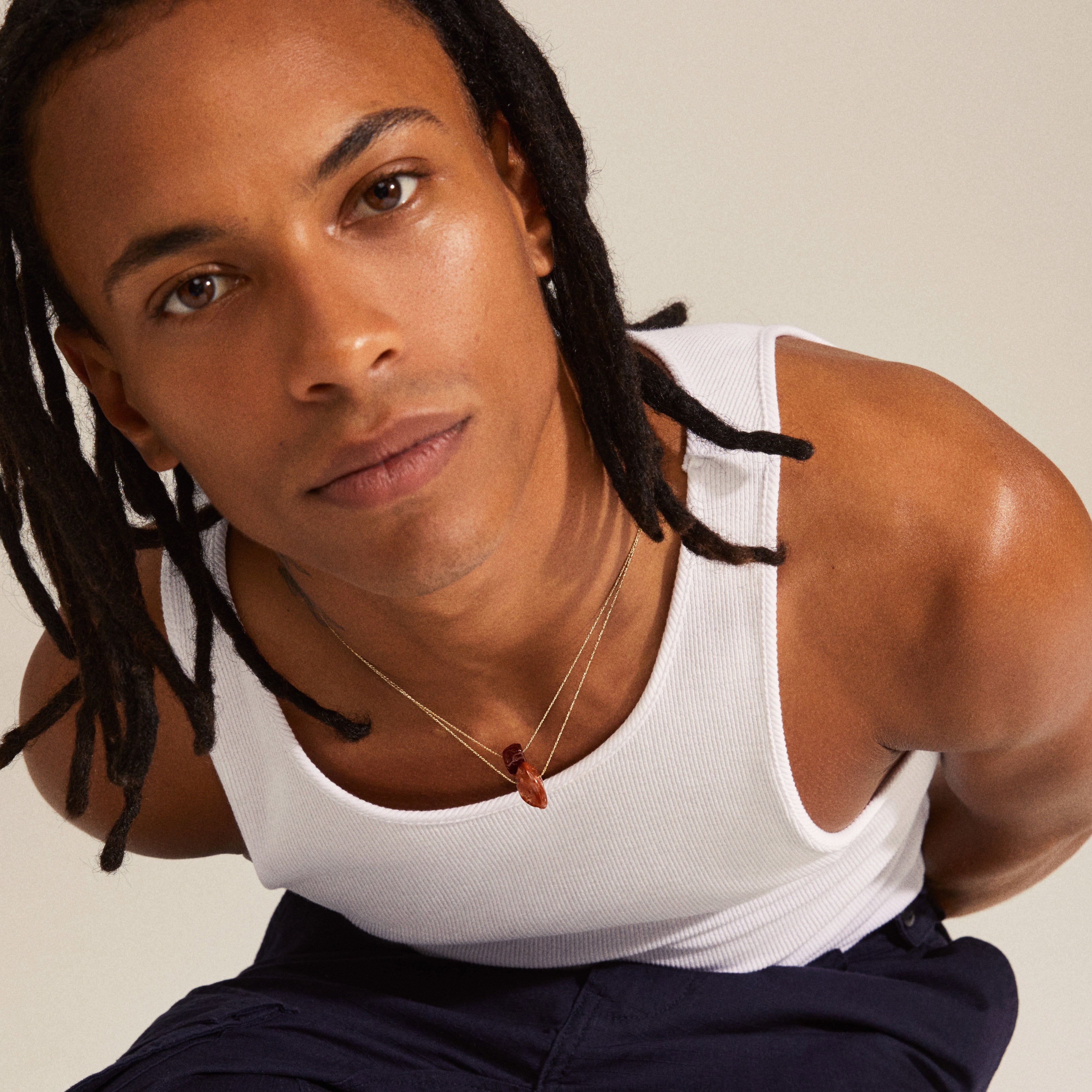 Man wearing CHAKRA Carnelian necklace gold-plated, featuring an orange carnelian pendant on chest, highlighting the necklace's simplicity and elegance.