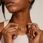 DAGMAR mini pendant necklace gold-plated, featuring a recycled material cross on a fine box chain, worn by a woman.