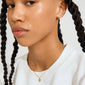 Close-up of the DAGMAR mini pendant necklace gold-plated on a person, showcasing a delicate gold chain with a small, reimagined Dagmar Cross pendant.