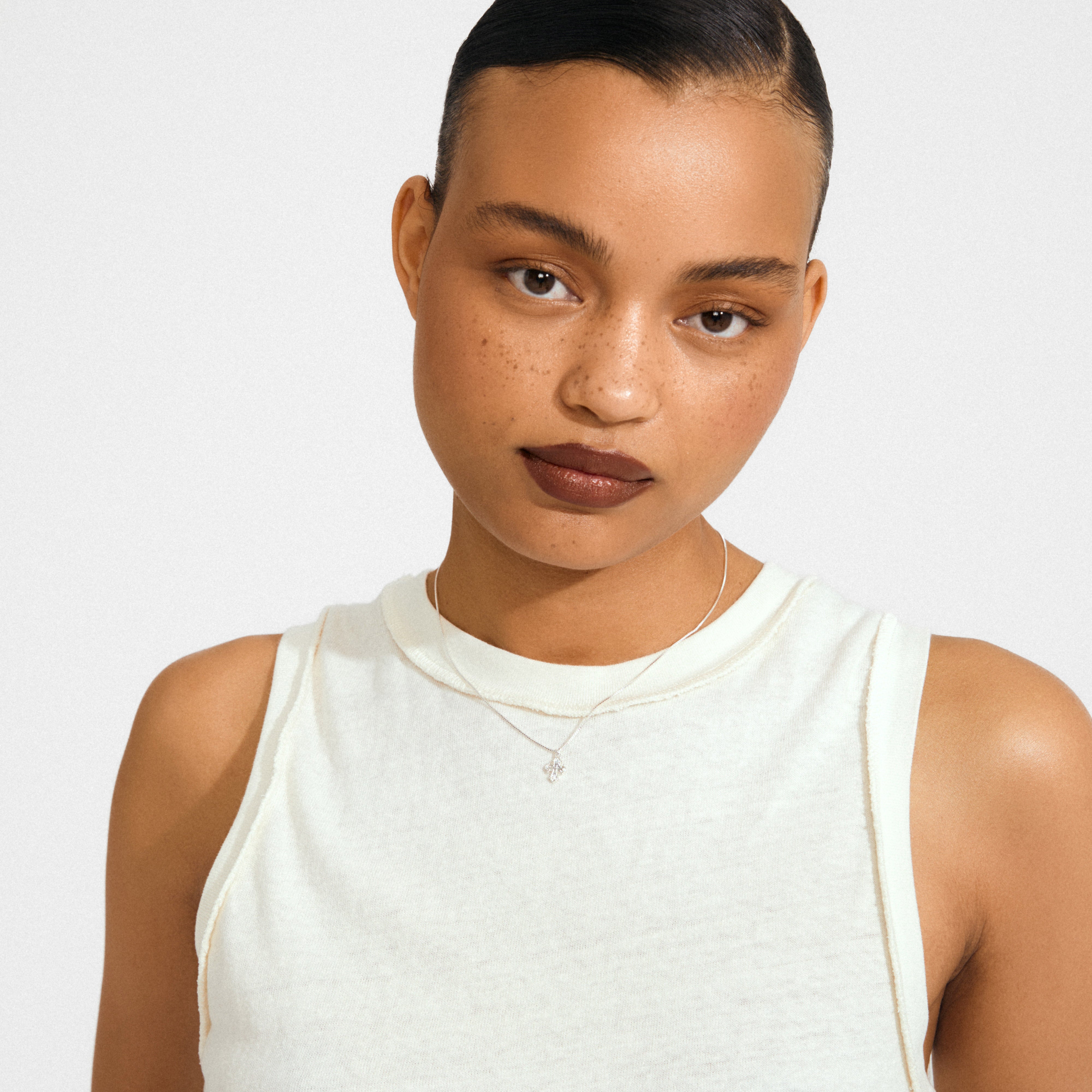 Young woman wearing the DAGMAR mini pendant necklace silver-plated, showcasing a delicate, silver-plated Dagmar Cross pendant on a fine chain, embodying minimalist Danish elegance.