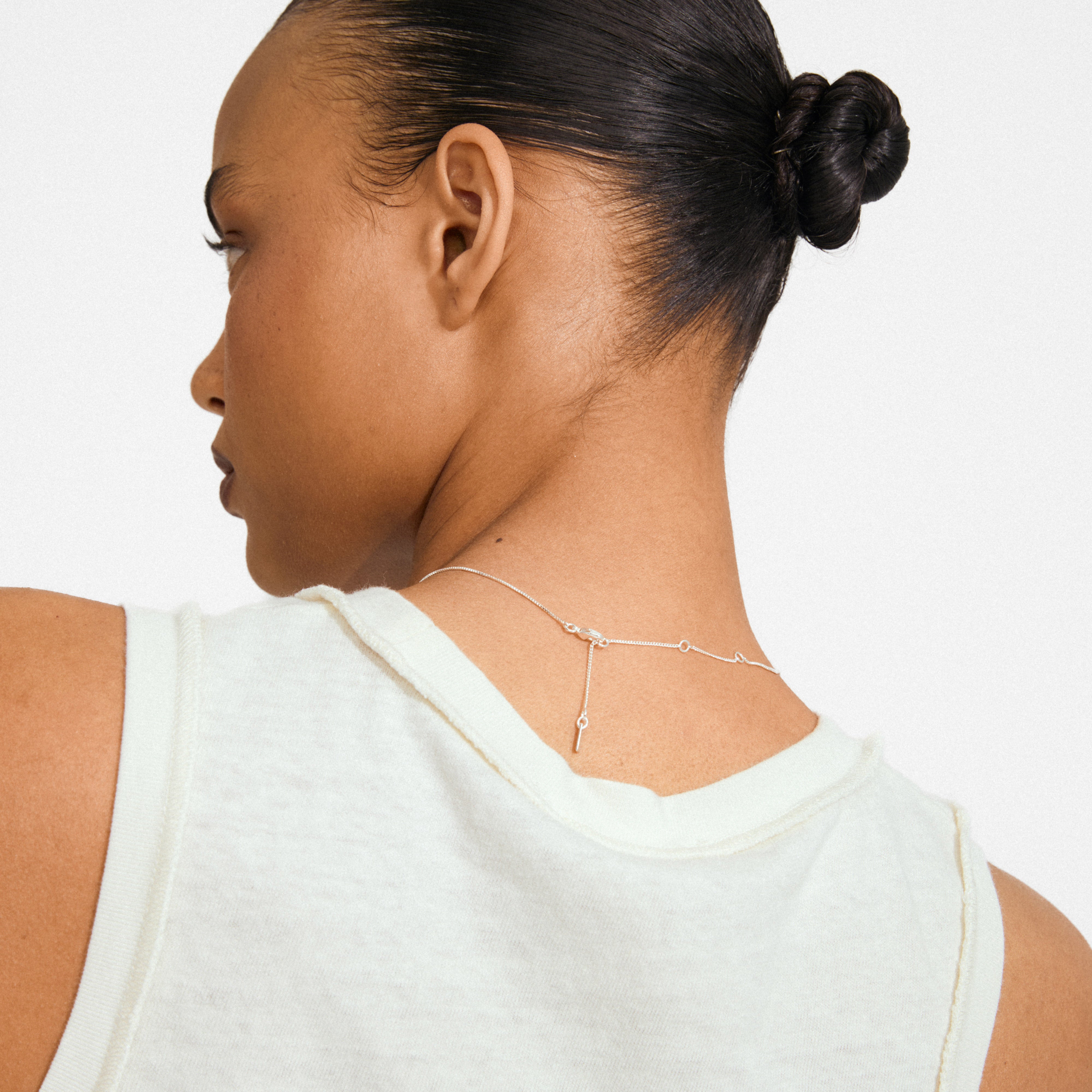 Back view of a person wearing the DAGMAR mini pendant necklace silver-plated, showcasing a fine silver chain and a mini Dagmar Cross pendant.
