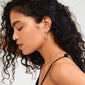 Close-up of a woman wearing Pilgrim's BREEZE gold-plated hoops with conch shell pendants, highlighting their beach-inspired design and easy click clasp.
