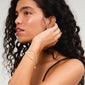 Woman with curly hair wearing the BREEZE bracelet, featuring a layered design with freshwater pearls and Preciosa crystals, embodying summer style.