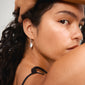 Close-up of a woman wearing Pilgrim's BREEZE silver-plated hoops with conch shell pendants, showcasing their elegant design and beach-inspired style.