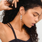 Close-up of a woman wearing BREEZE chain earrings, featuring asymmetrical silver-plated chains with freshwater pearls, capturing a dreamy, boho-chic style.