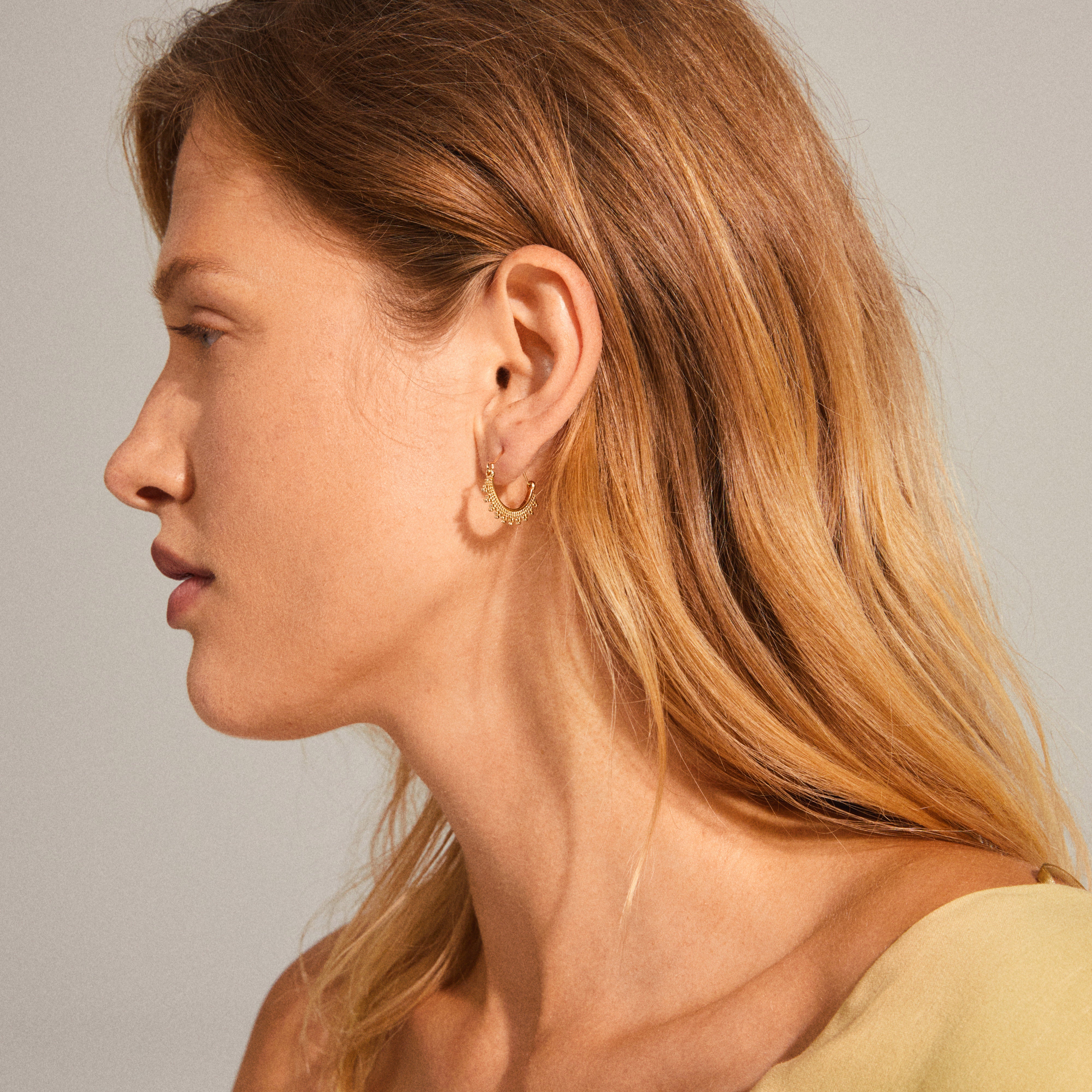 KIKU half hoop earrings, gold-plated with Asian-inspired patterns, elegantly displayed on a woman's ear, showcasing their intricate design and bohemian flair.