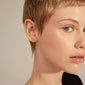 BRIELLE gold-plated earrings on a woman with short hair, featuring a minimalist transverse bar and delicate chain for a stylish, versatile look.