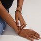 Person wearing the INDIE bracelet, featuring glittering, faceted white glass beads and a discreet gold-plated Pilgrim logo, on their wrist.