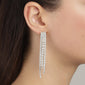 Close-up of RACHEL earrings, silver-plated, with cascading, sparkling crystals hanging elegantly from a woman's ear, capturing light like a shimmering waterfall.