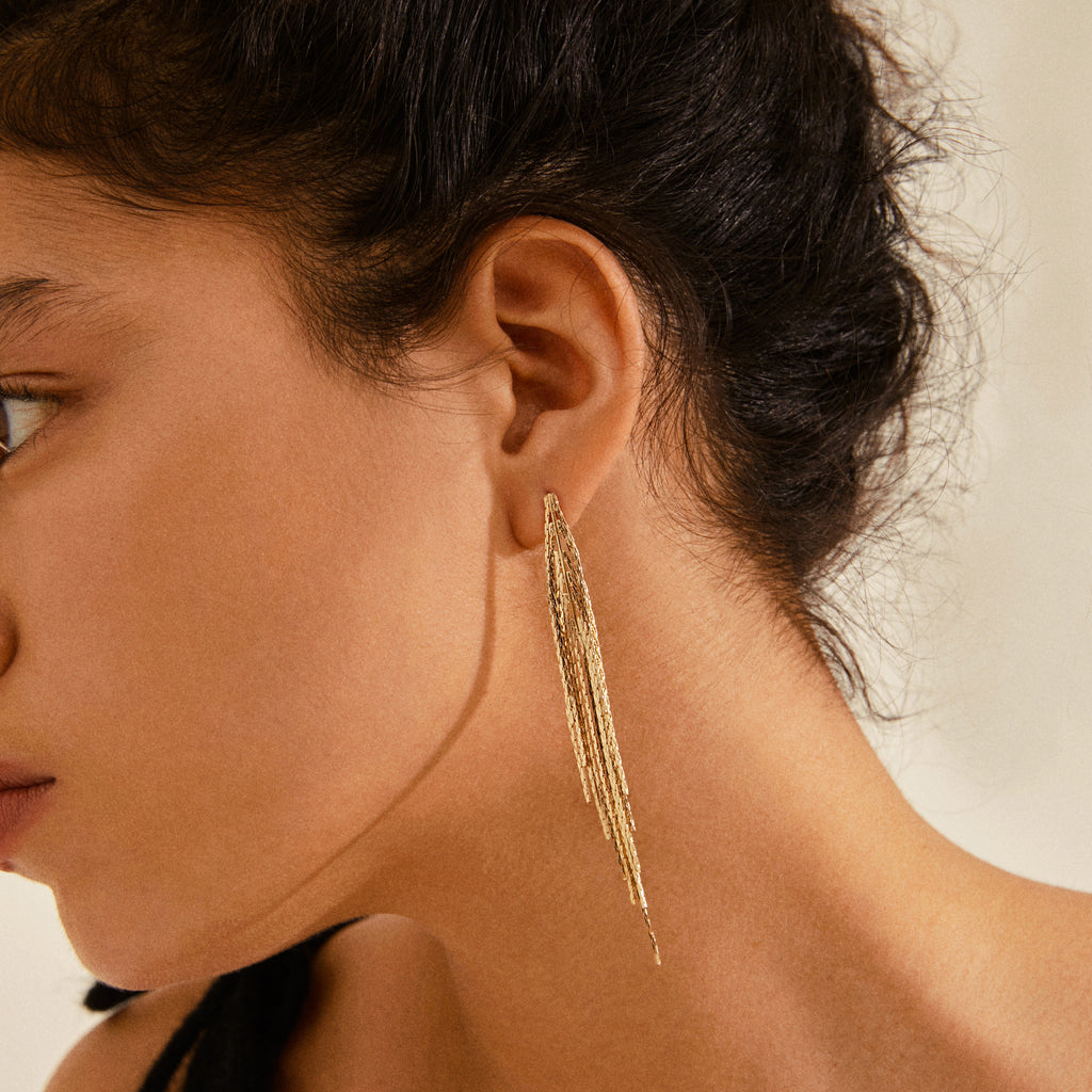 Woman wearing CARMEN waterfall earrings gold-plated, showcasing long, elegant chains that exude feminine energy and class, aligning with Pilgrim's timeless, trendy style.
