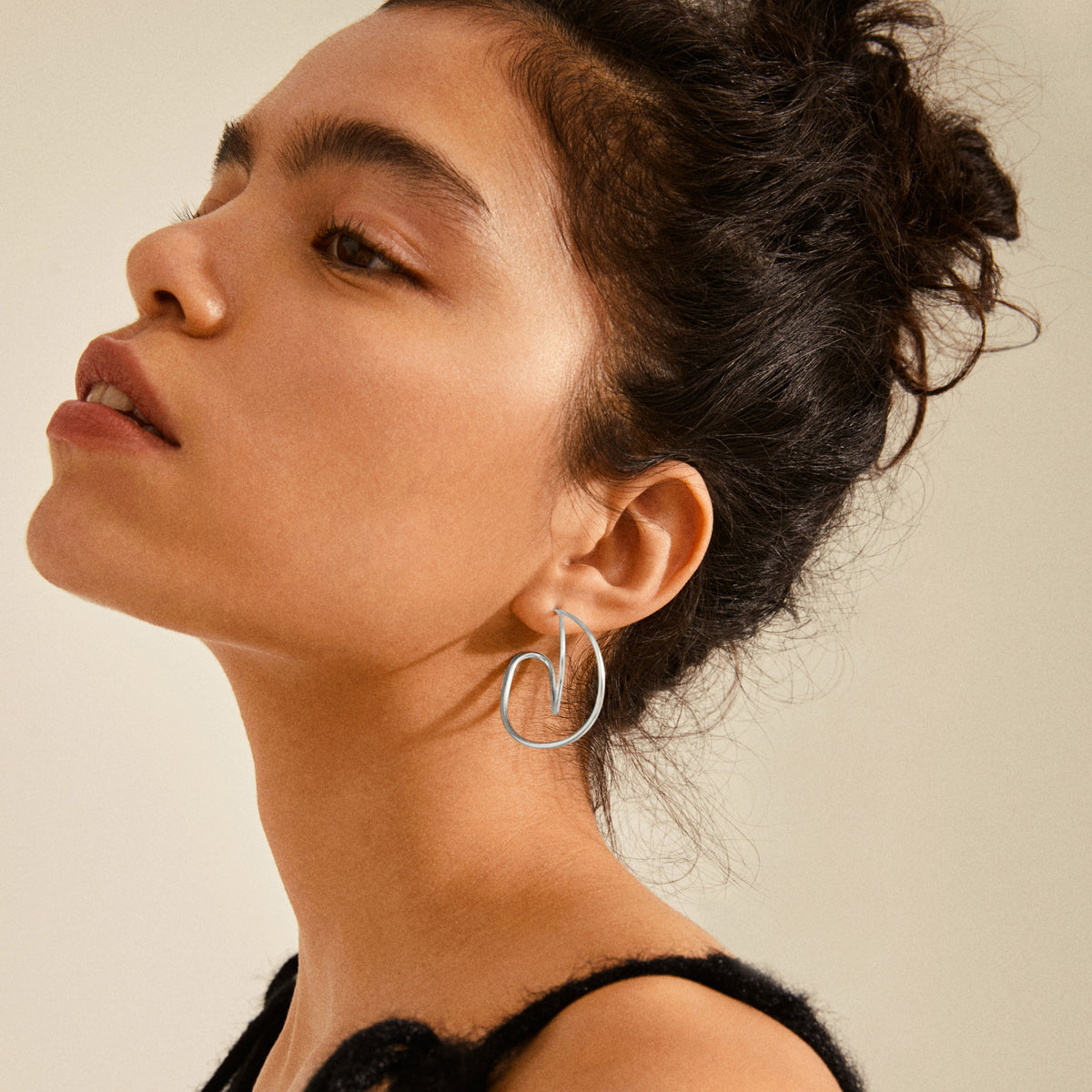 Young woman wearing MILLER graphic statement earrings silver-plated, featuring elegant, drop-shaped design, highlighting Pilgrim's blend of timeless and trendy Scandinavian craftsmanship.