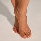 Close-up of a foot wearing the ELKA ankle chain 2-in-1 silver-plated by Pilgrim, featuring two delicate chains with round pendants for a stylish summer look.