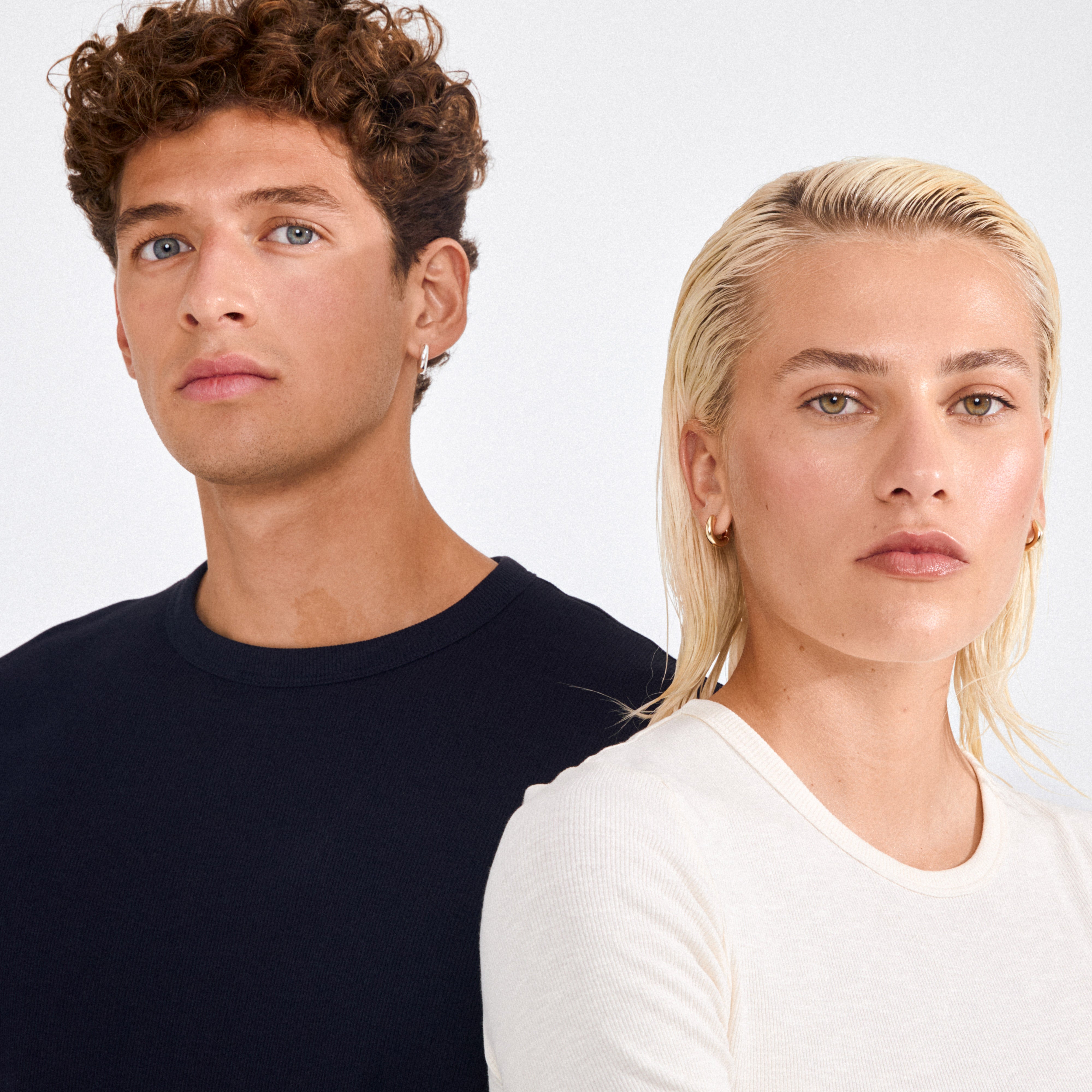 Two young adults wear Pilgrim’s AICA chunky gold-plated huggie hoop earrings, showcasing their bold, minimalist design and polished finish.