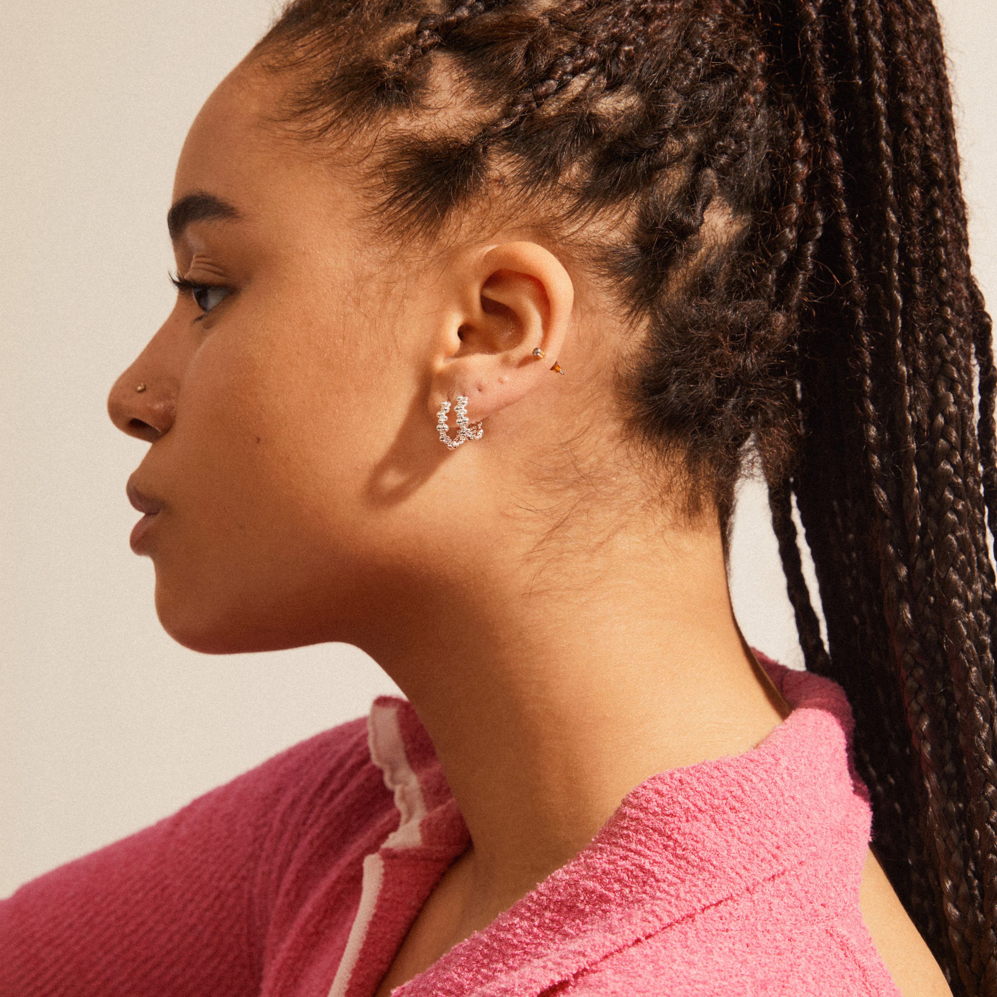 Close-up of a woman wearing silver-plated SOLIDARITY medium bubble hoops, showcasing their playful, asymmetric design and dynamic silhouette.