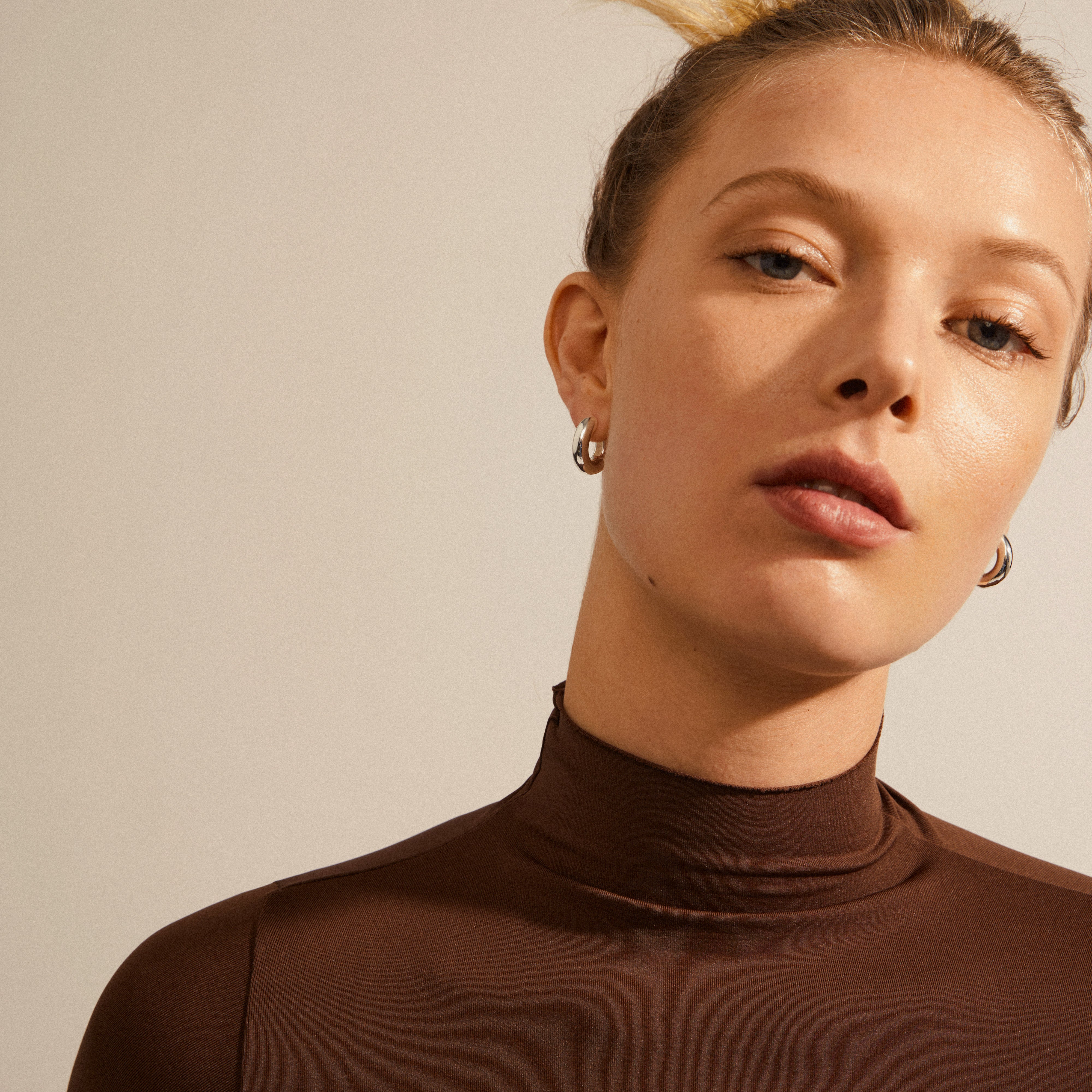 Woman wearing AICA chunky hoop earrings, silver-plated, showcasing their medium size and chunky silhouette. Perfect for everyday style, emphasizing Pilgrim's timeless design.