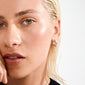 Close-up of AICA chunky hoop earrings, silver-plated, on a fair-skinned individual with slicked-back hair, showcasing minimalist style and eco-friendly craftsmanship by Pilgrim.