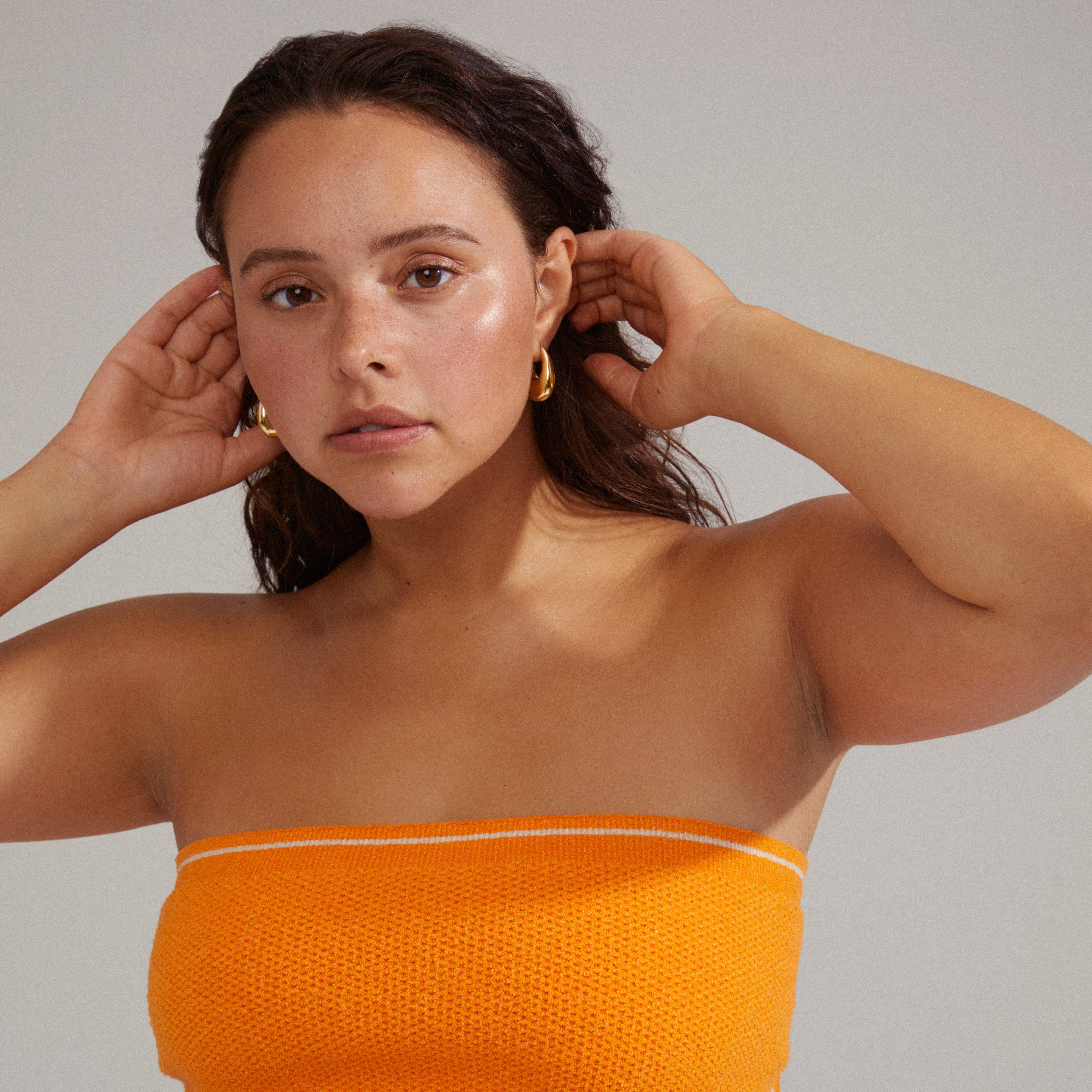 Woman wearing AUTUMN chunky retro hoop earrings, gold-plated, showcasing teardrop design and robust look, enhancing her stylish and vintage-inspired appearance.