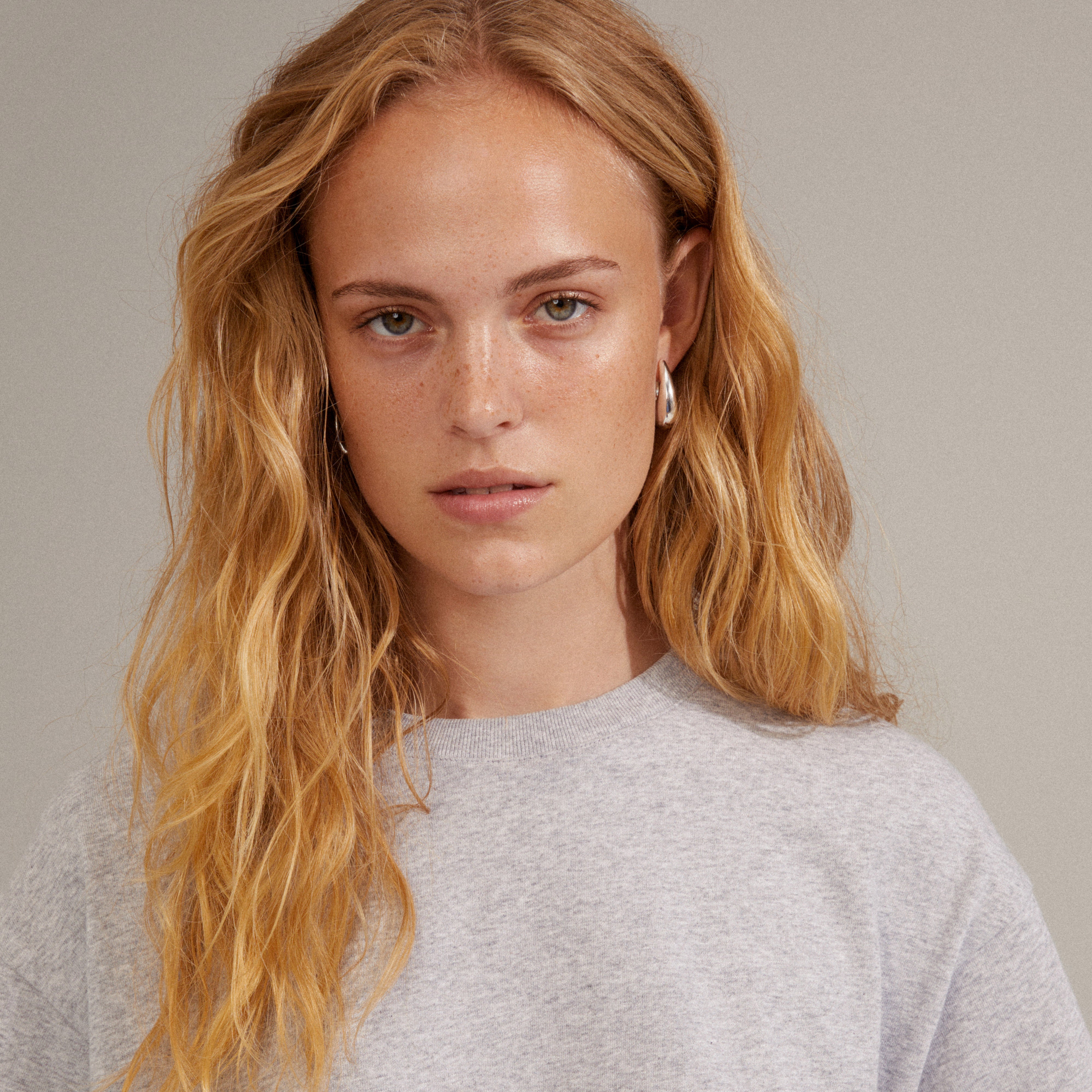 Close-up of a woman wearing silver-plated AUTUMN chunky retro hoop earrings, highlighting their teardrop design and robust, stylish look.