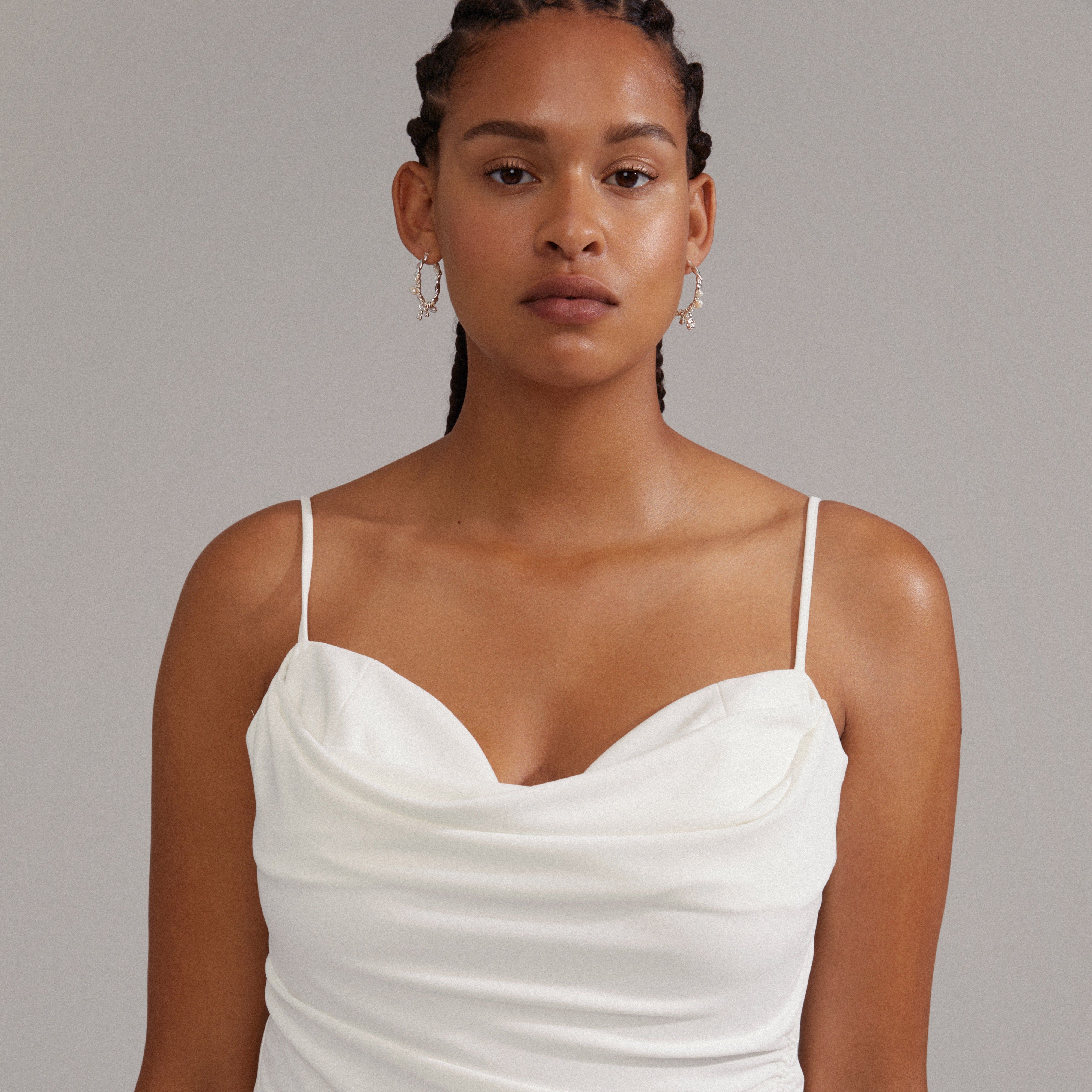 A woman wearing ANA pearl & crystal hoops silver-plated, showcasing twisted design with freshwater pearls and Preciosa crystals, complementing her elegant white dress.
