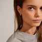 Close-up of a woman wearing MATYLDA crystal hoop earrings, gold-plated with Preciosa crystals, highlighting their classy and sparkling design.