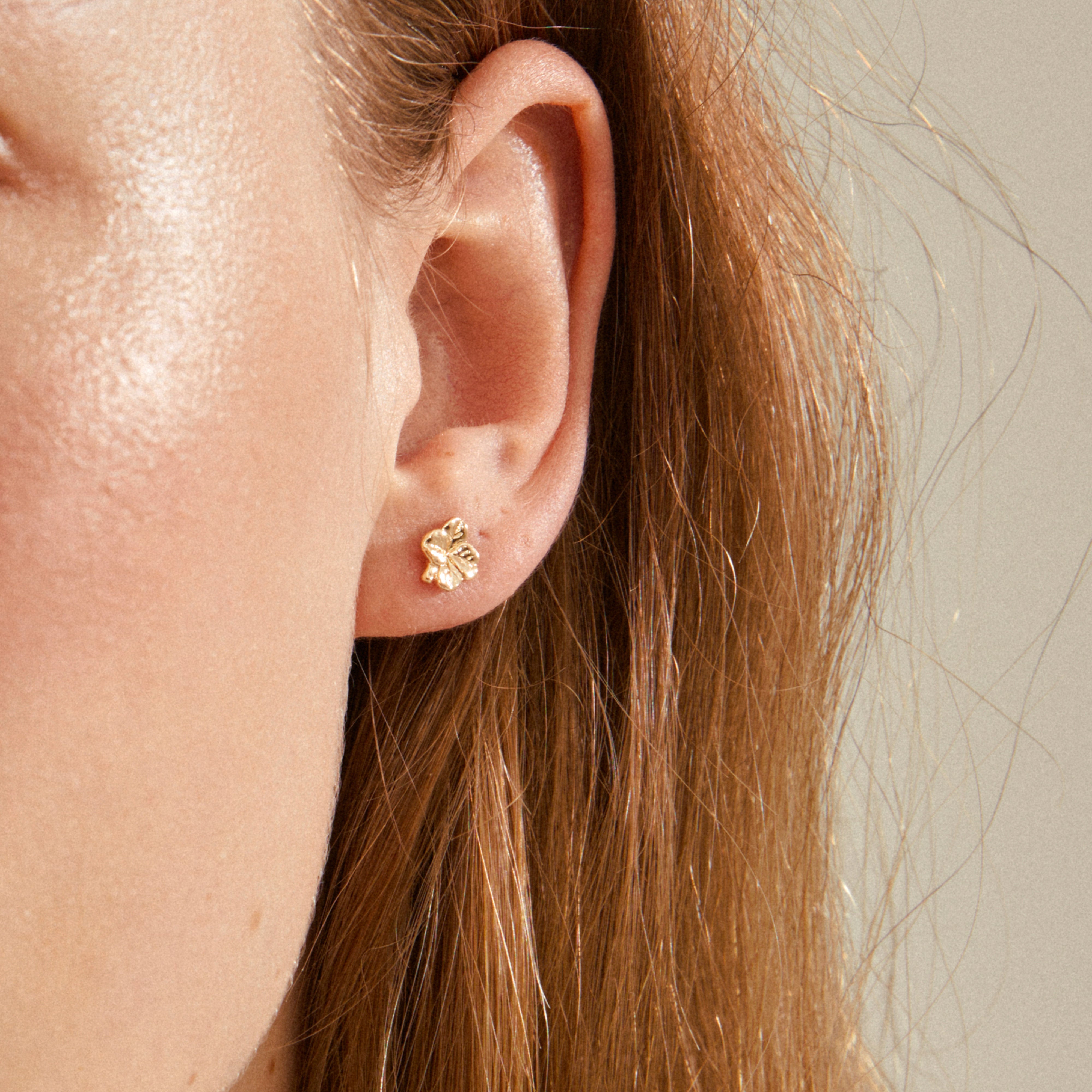 OCTAVIA clover earrings gold-plated on an ear, featuring a delicate floral design symbolizing luck. Perfect for everyday wear and eco-friendly, made from 85% recycled materials.