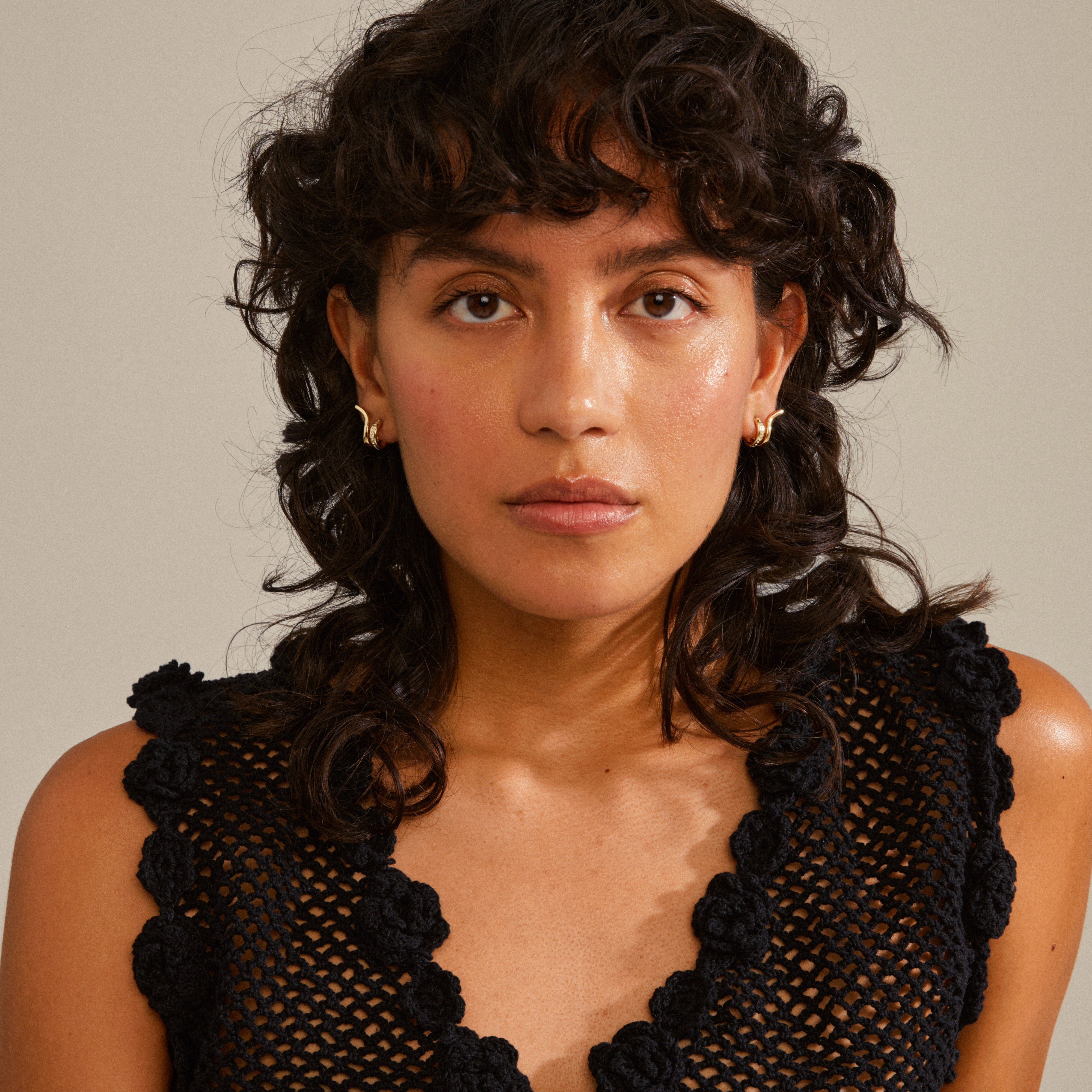 NADINE gold-plated earrings displayed on a woman with curly hair, showcasing their trendy ear crawler effect and shiny finish with tiny Preciosa crystals.