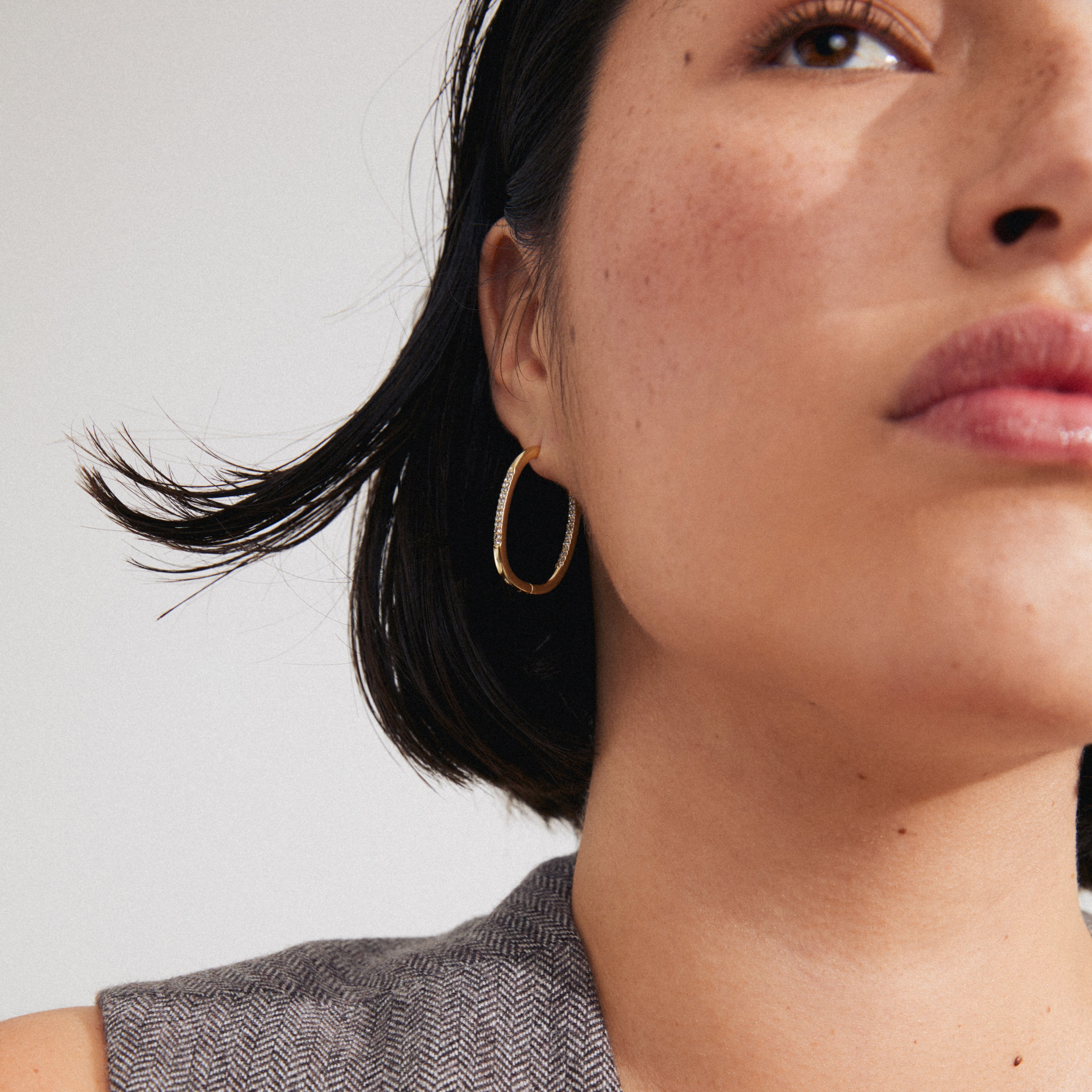 Woman with short haircut wearing Pilgrim's STAR gold-plated hoops adorned with Preciosa crystals, showcasing a stylish, elegant look.
