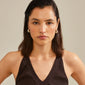Woman wearing black tank top showcasing NAOMI crystal hoops, gold-plated, from Pilgrim. Hoops feature chunky design with Preciosa crystals, emphasizing sustainability and style.