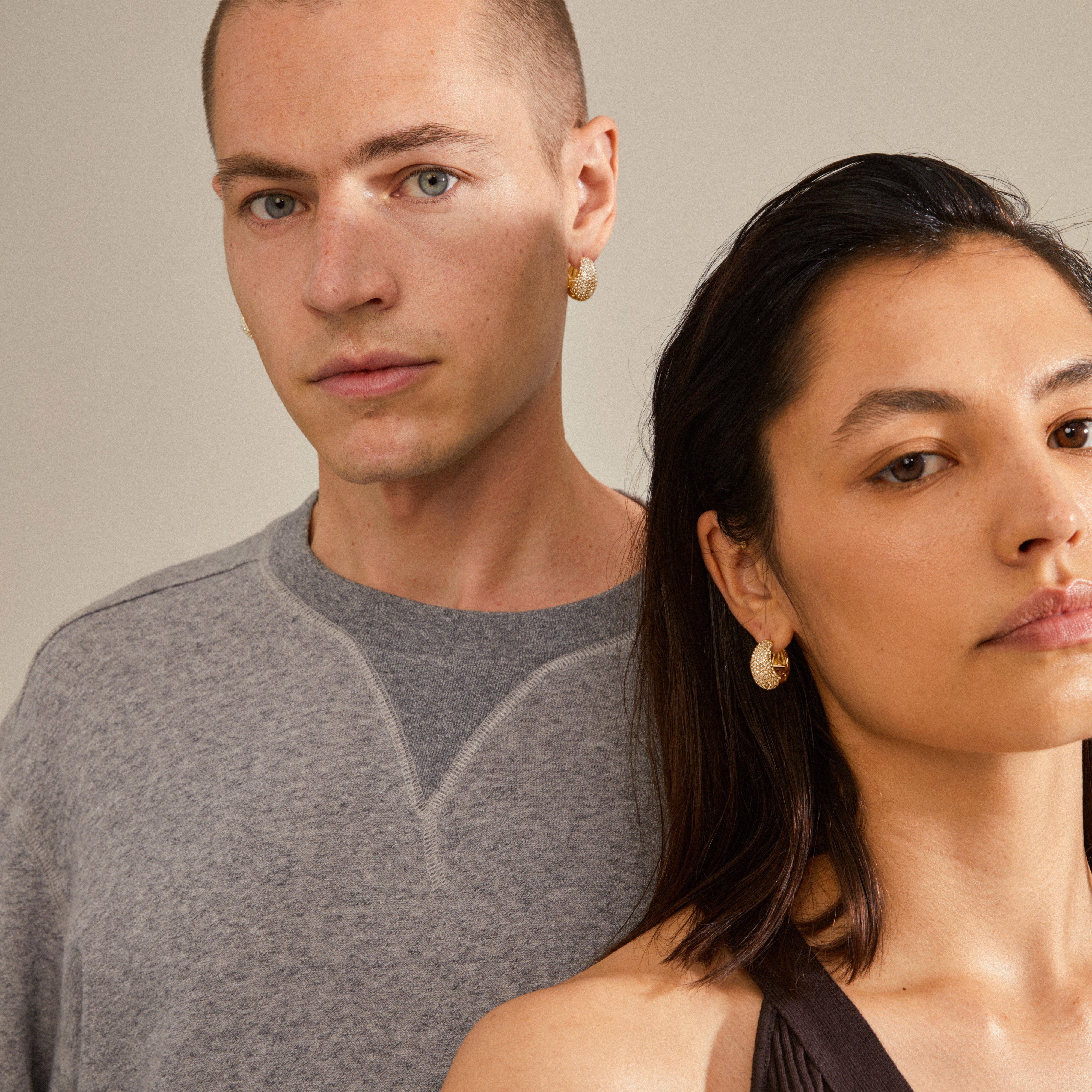NAOMI crystal hoops gold-plated, featuring chunky design with Preciosa crystals for a sophisticated look, worn by a woman, showcasing Pilgrim's eco-conscious, trendy jewelry.