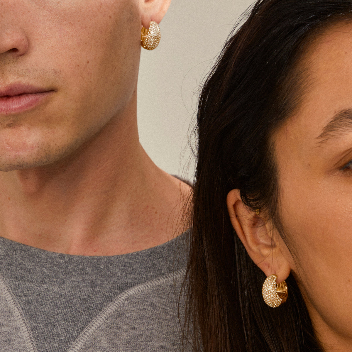 Two people showcase NAOMI crystal hoops gold-plated, highlighting their chunky pavé-set design with sparkling crystals, embodying Pilgrim's blend of trendiness and sustainability.