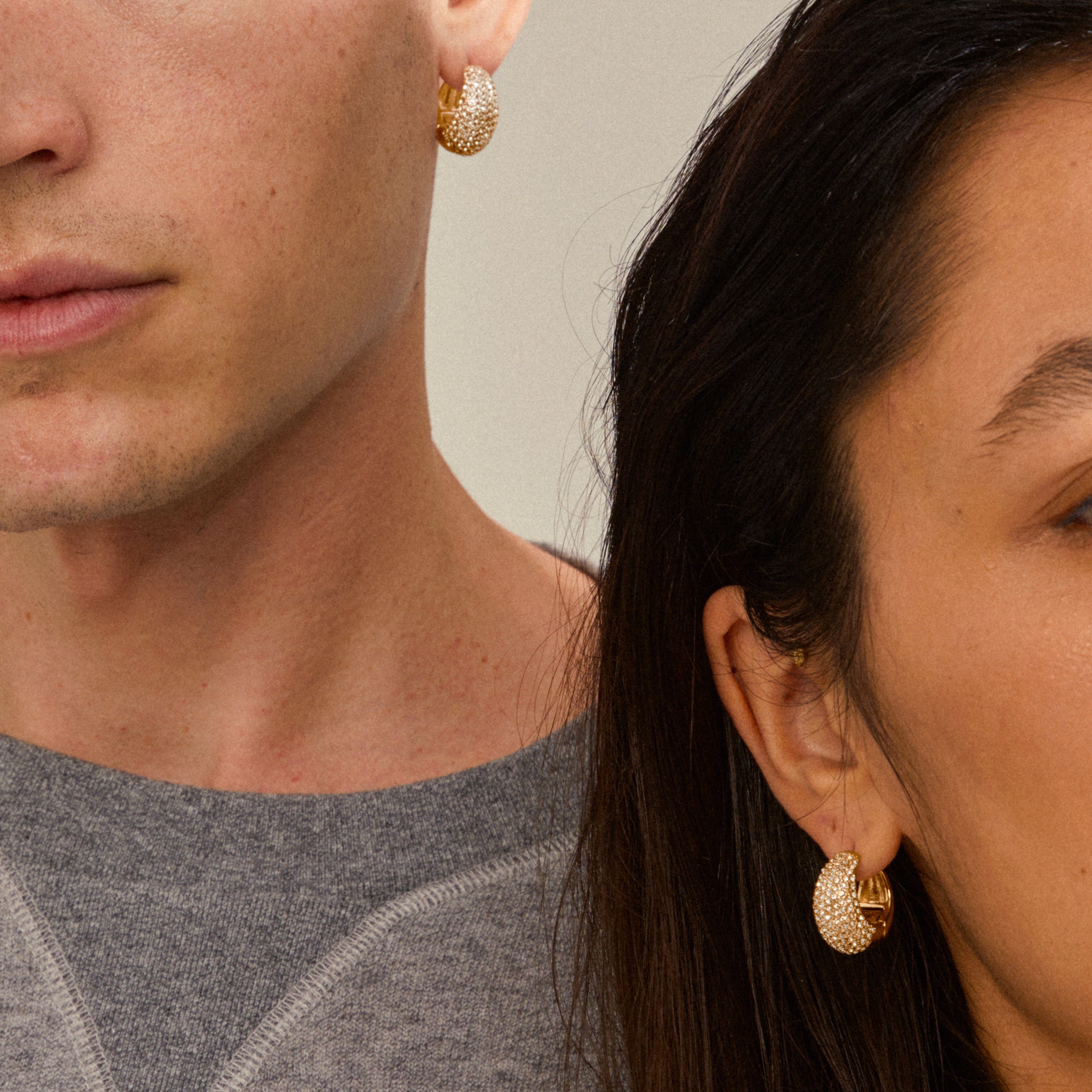 Two people showcase NAOMI crystal hoops gold-plated, highlighting their chunky pavé-set design with sparkling crystals, embodying Pilgrim's blend of trendiness and sustainability.
