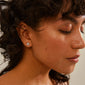 OCTAVIA clover earrings silver-plated on a woman's ear, eyes closed, showcasing the timeless four-leaf clover design symbolizing luck and positivity.
