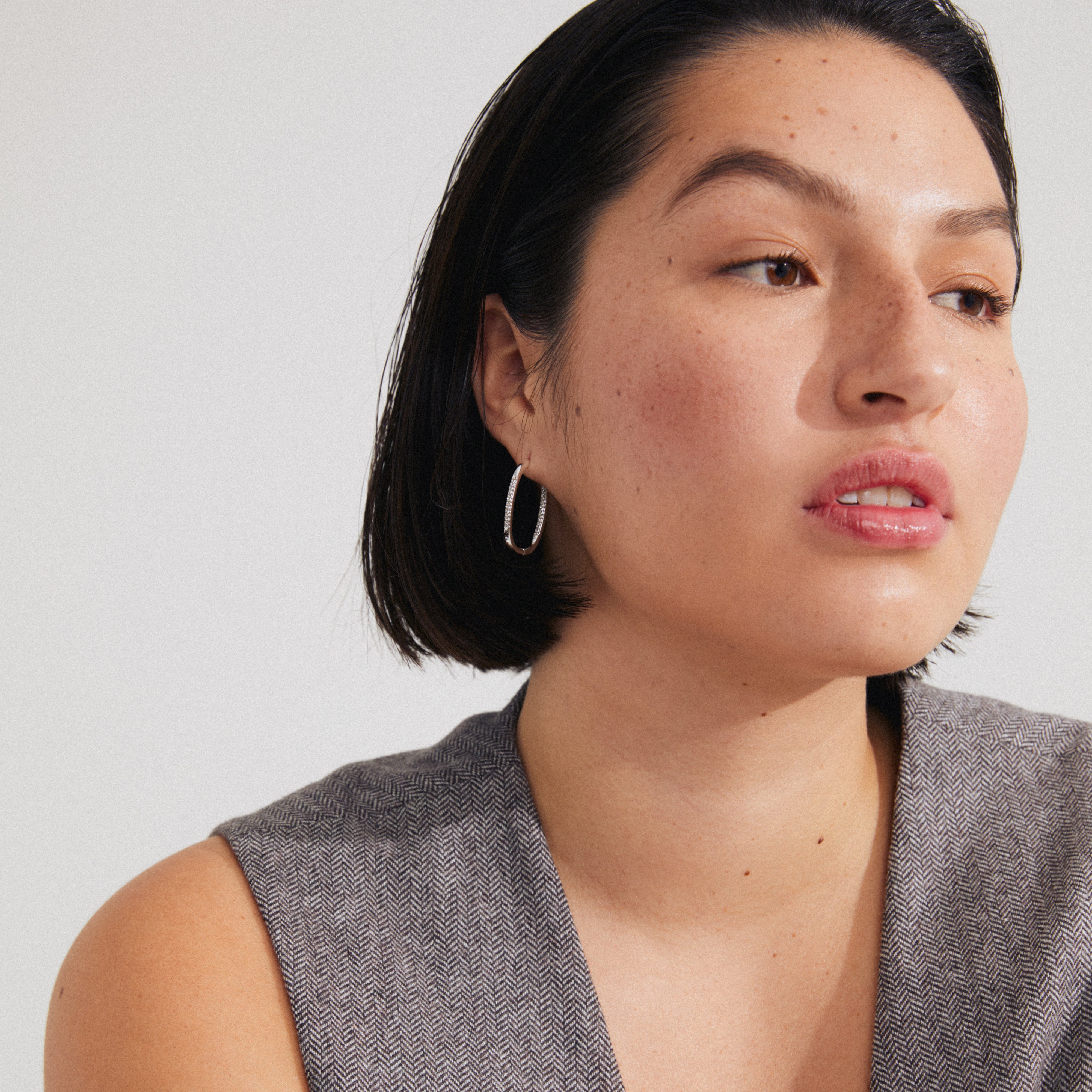 Close-up of a woman wearing STAR hoops silver-plated earrings with sparkling Preciosa crystals from Pilgrim's collection, showcasing their luxurious, eco-friendly design.