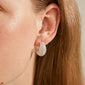 Close-up of an ear wearing NAOMI crystal hoops, silver-plated huggie earrings encrusted with sparkling Preciosa crystals, offering a sophisticated, eco-friendly style.
