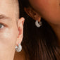 NAOMI crystal hoops silver-plated, showcased on diverse models, feature pavé-set Preciosa crystals in a sleek half-hoop design, embodying Pilgrim's blend of elegance and sustainability.