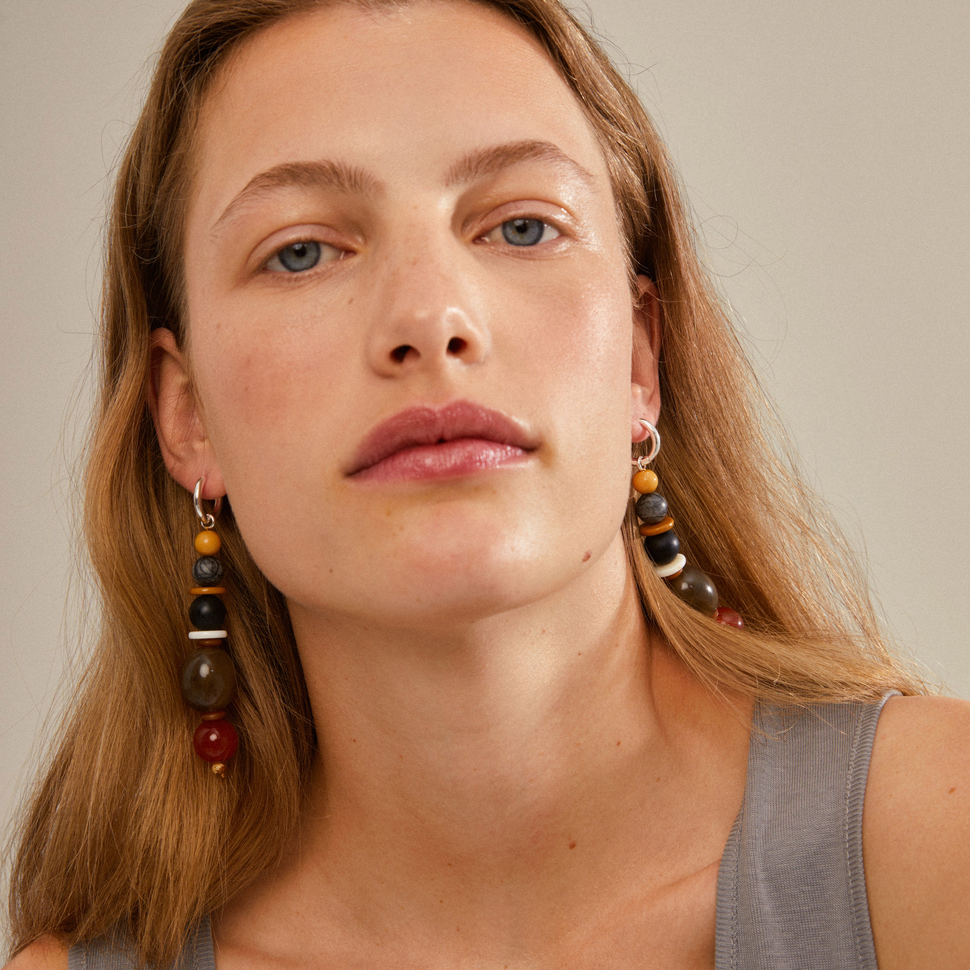 Woman wearing NAILA earrings, multi-coloured/silver-plated, featuring eye-catching beaded design and silver-plated hoops; perfect for adding a statement to any outfit.