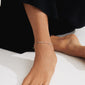 Close-up of a person's ankle adorned with the ALISON ankle chain by Pilgrim, featuring pink glass beads and mother-of-pearl accents.
