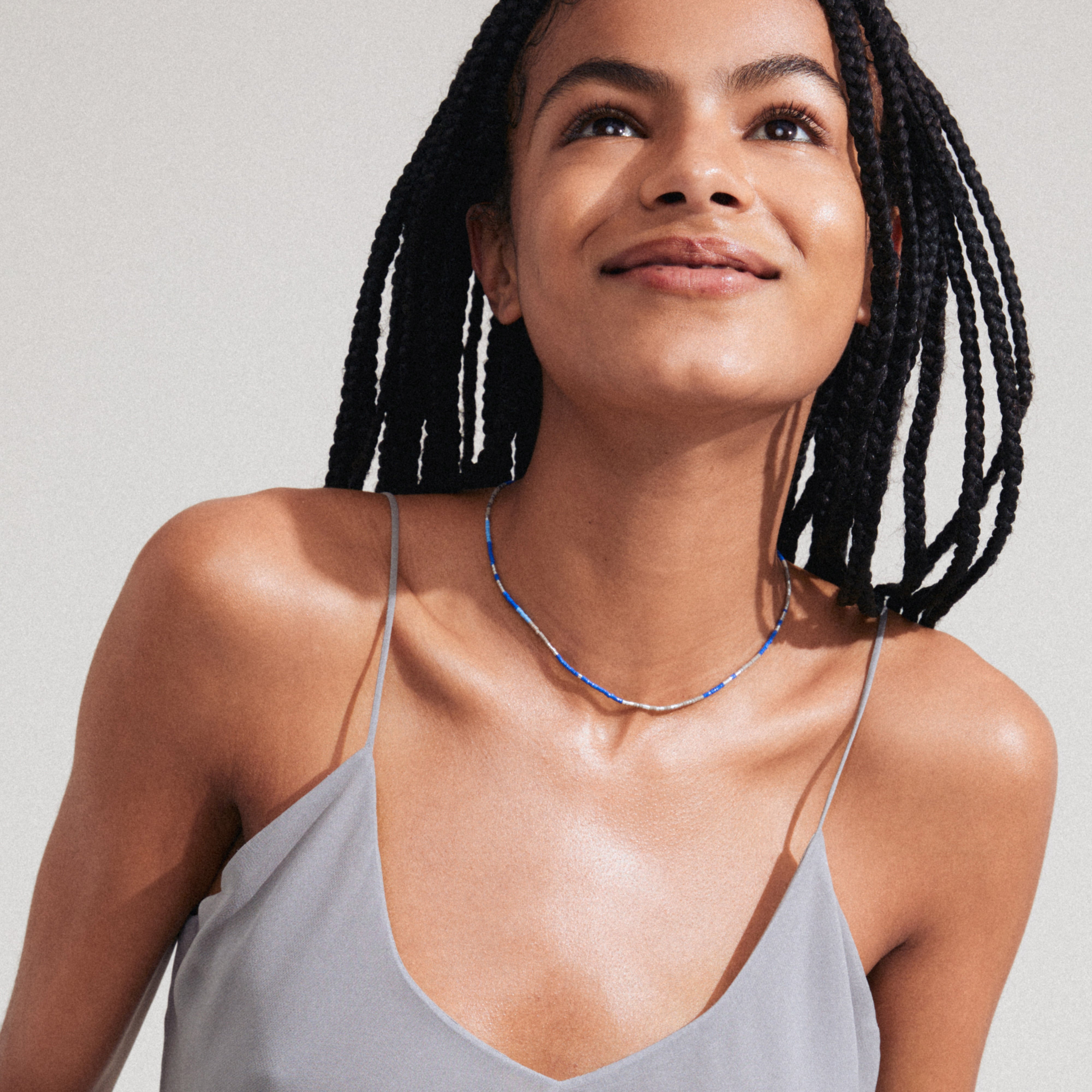 Woman wearing Pilgrim's ALISON necklace, blue silver-plated, featuring glass beads, styled for a relaxed, layered look.