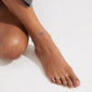 Close-up of the blue ALISON ankle chain with silver-plated glass beads on a person's ankle, highlighting its slender, boho-chic design from Pilgrim.
