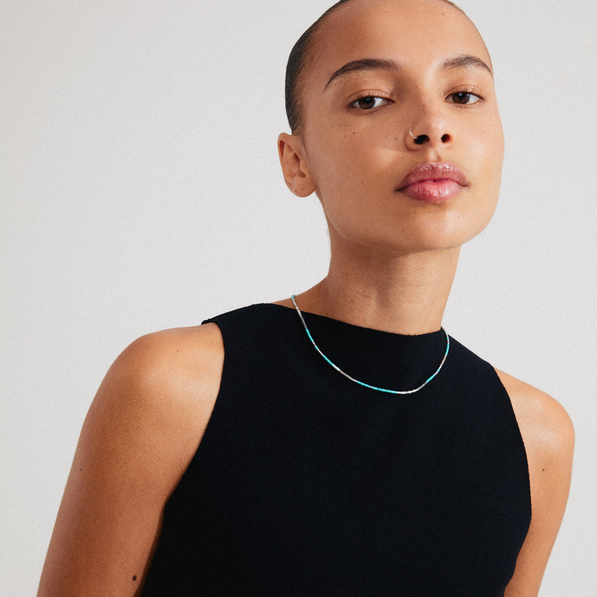 Woman wearing the ALISON necklace, featuring mint green and grey glass beads, worn close to the neck for a stylish, layered look.